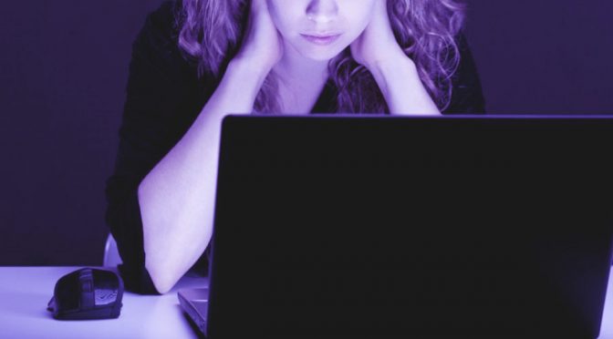 mulher diante do computador com feição séria e postura preocupada